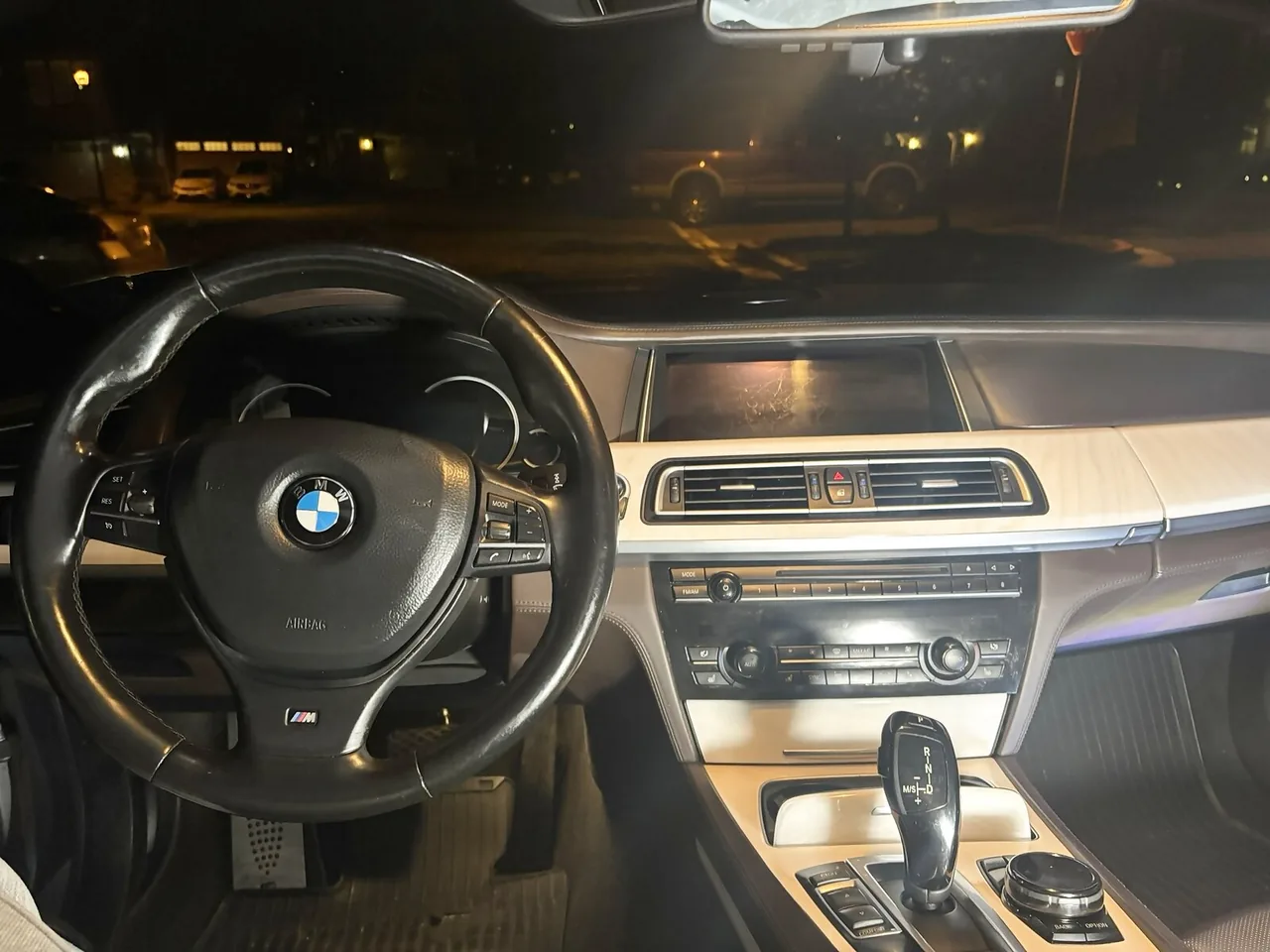 2015 BMW 750Li from the driver's seat at night before the upgrade, with the original BMW iDrive display